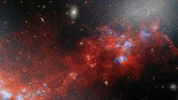 A glowing cloud of red gas and dust mixed in with bright dots for stars in deep space