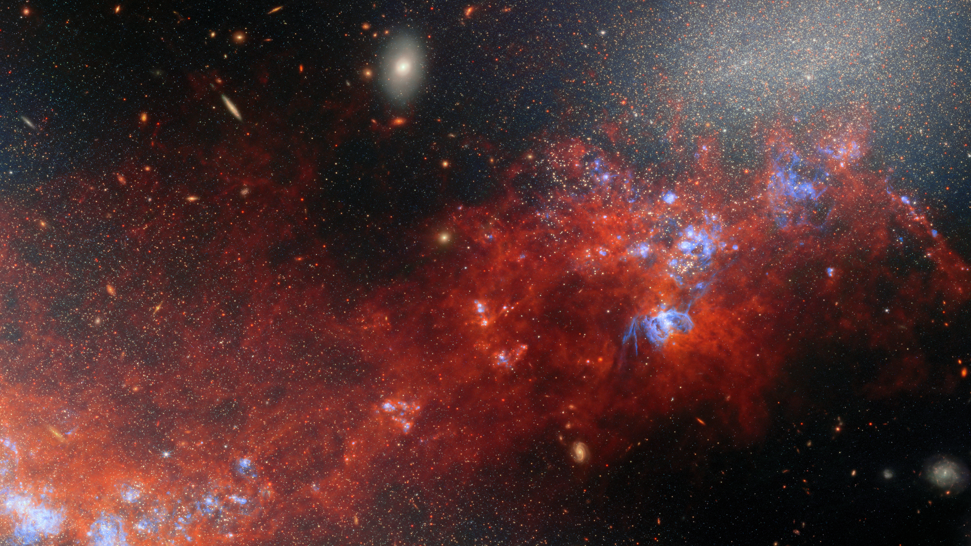 A glowing cloud of red gas and dust mixed in with bright dots for stars in deep space