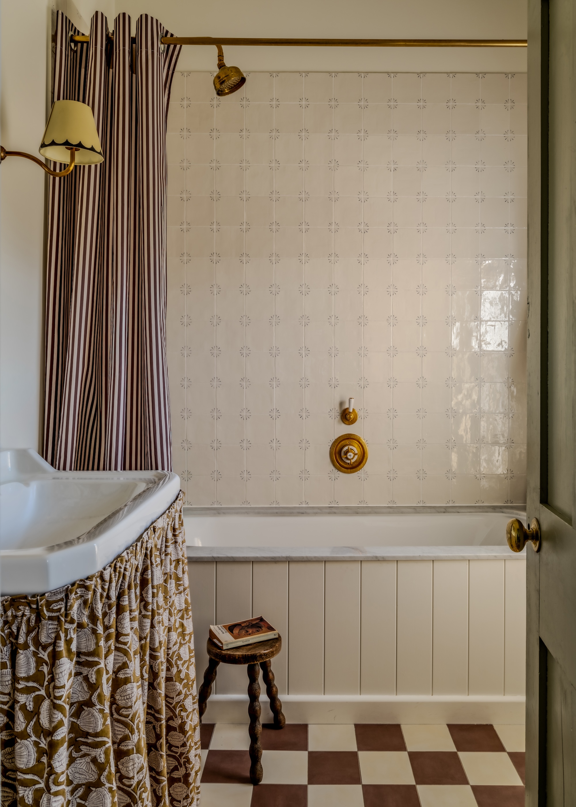 A compact yet personality packed bathroom shown with off white walls, Delft style tiles, a checkerboard floor and basin skirt
