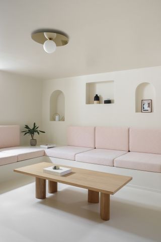A living room in muted tones with a soft pastel built in seater
