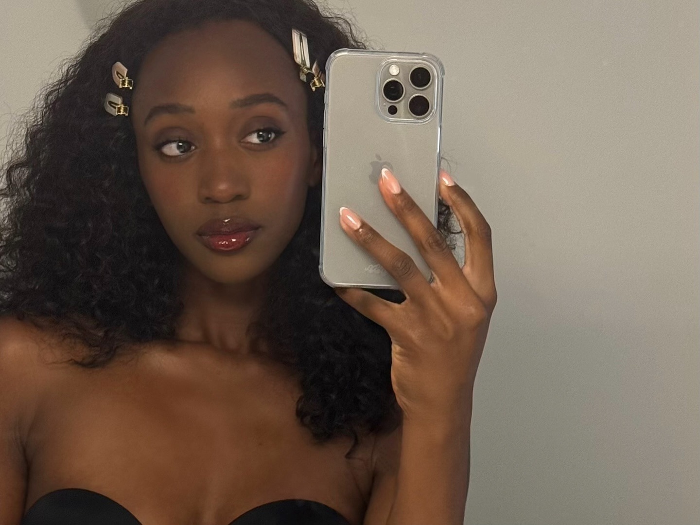 A woman with curly hair taking a selfie in a mirror