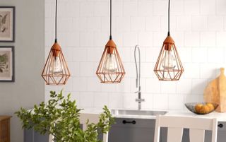 3 orange caged pendant lights over a kitchen island