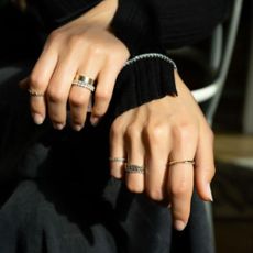 Two hands wearing gold and silver rings with black top