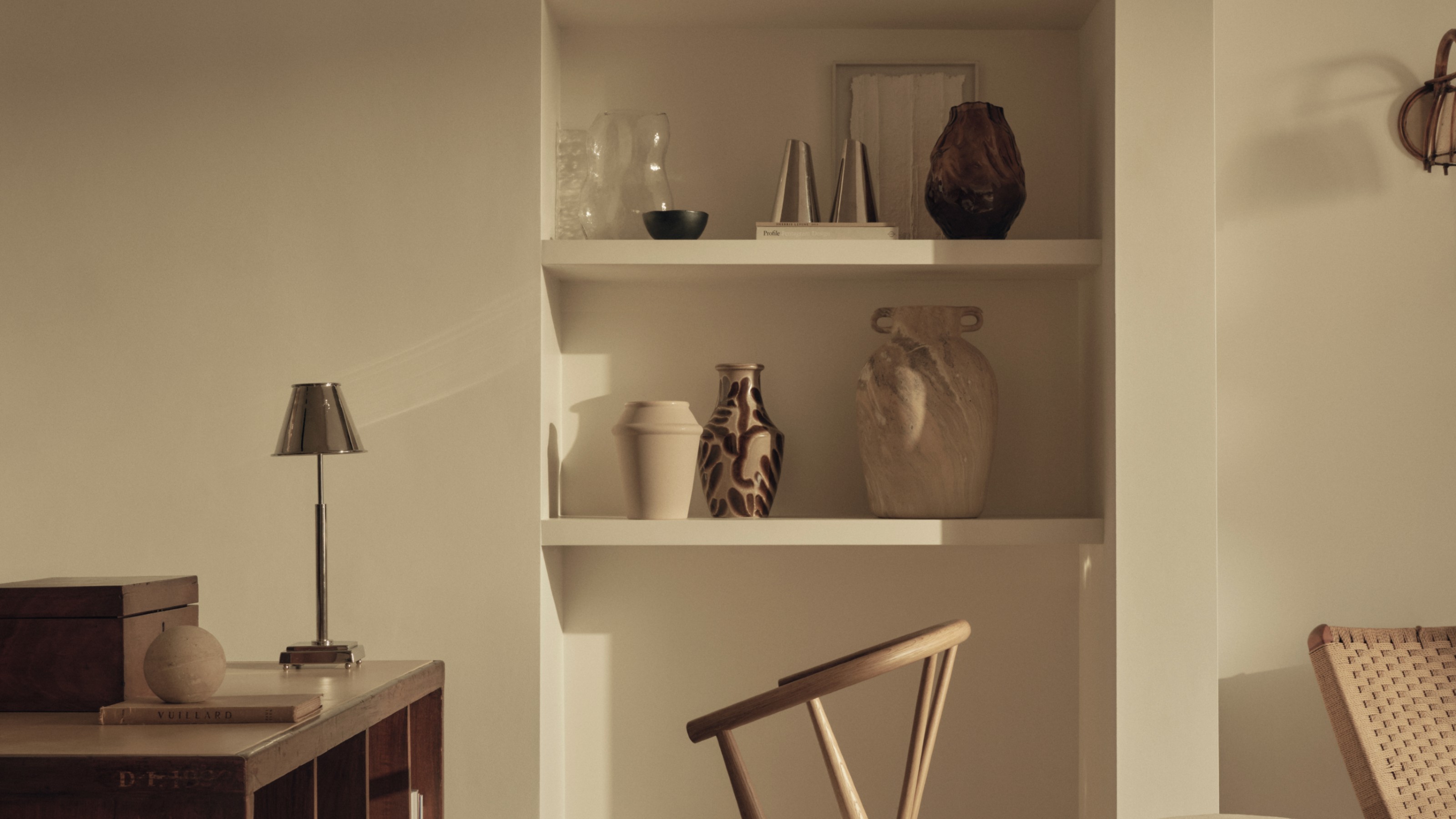 A white-painted room with built-in shelves displaying decorative vase and a desk with a rechargeable M&amp;S table lamp 