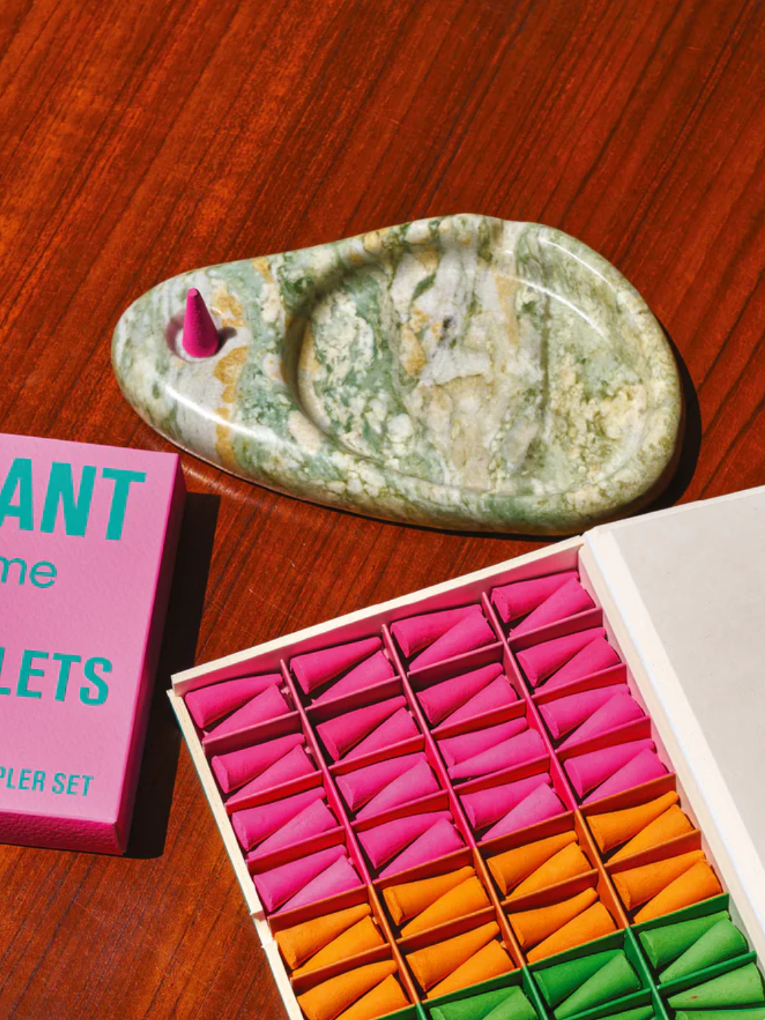 A green marble incense holder beside a box of colorful incense cones from Seth Rogen x Ripple+