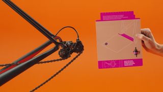 A view of the rear of a bike and the dropout cards from the Zwift Hub on an orange background