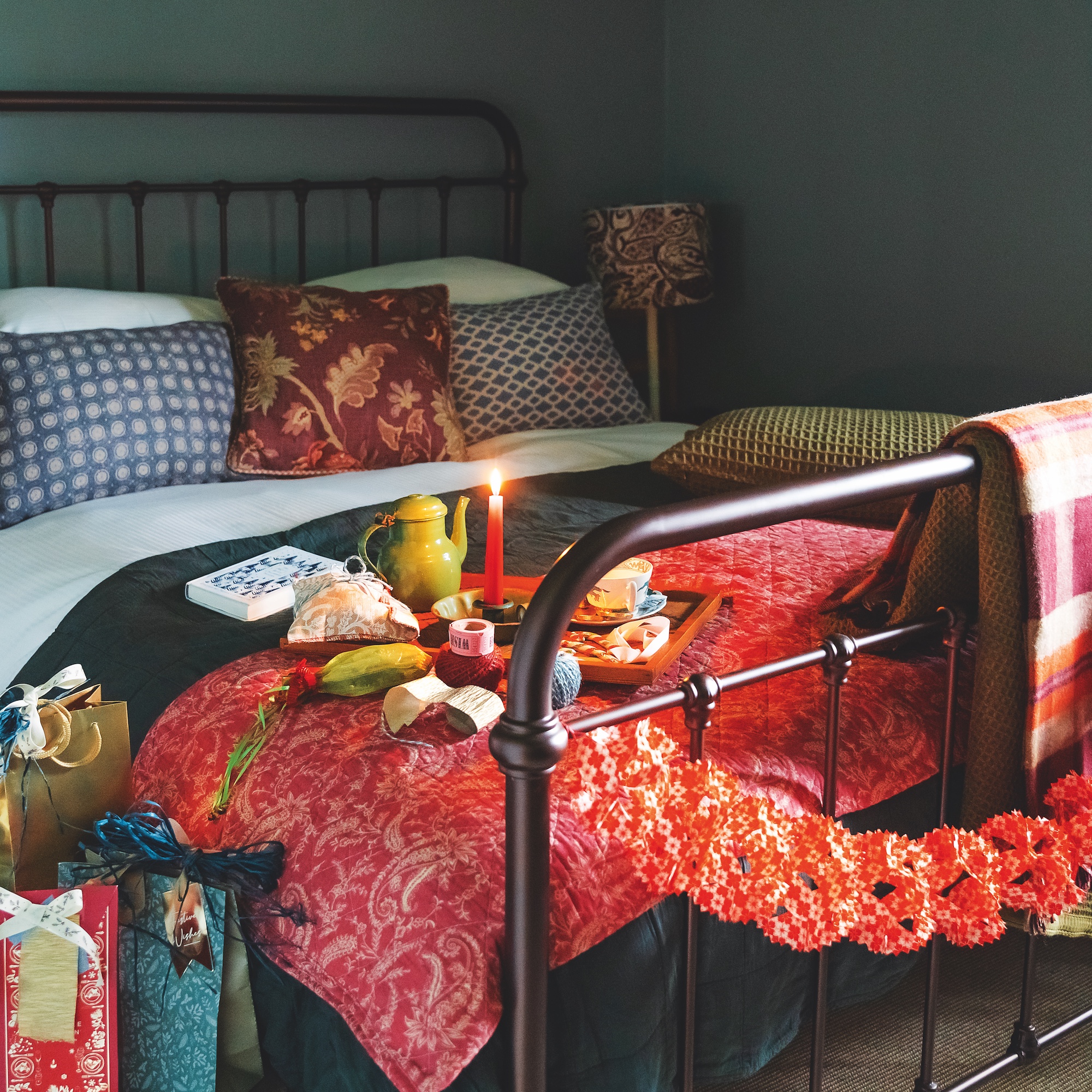 bedroom with iron double bedstead with orange quilt and blue and white check cushions