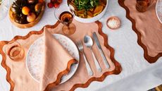 White tablecloth with peach and terracotta scalloped placemats and napkins