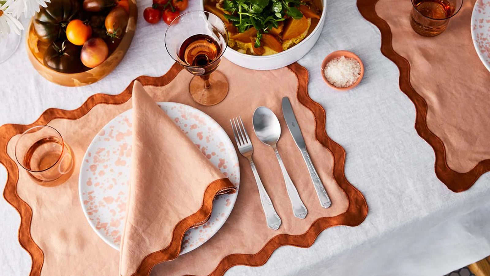 White tablecloth with peach and terracotta scalloped placemats and napkins