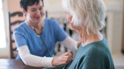 Older woman has her heart checked by a nurse with a stethoscope 