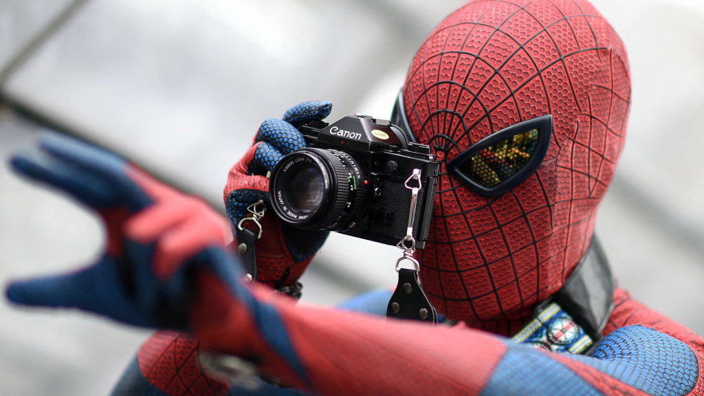 A visitor in a costume of fictional superhero Spiderman takes pictures during the Leipzig Book Fair on March 14, 2015.