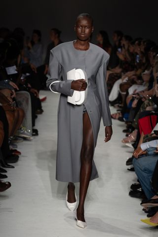 16Arlington model wearing a gray dress with a white bag and matching heels on the S/S24 runway.
