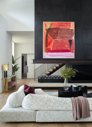 living room with high wall in dark grey hiding staircase and red artwork