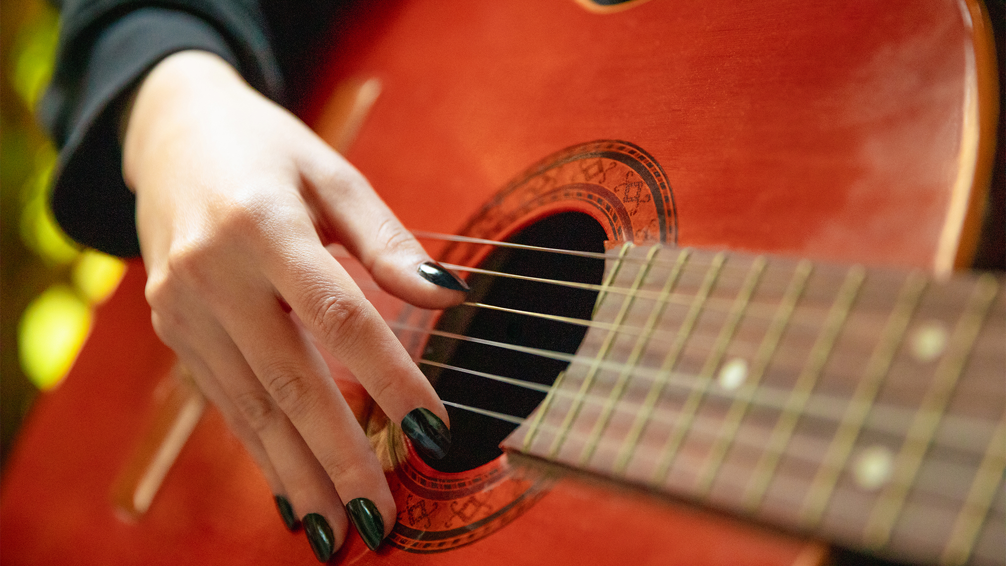Young woman playing acoustic guitar close up finger