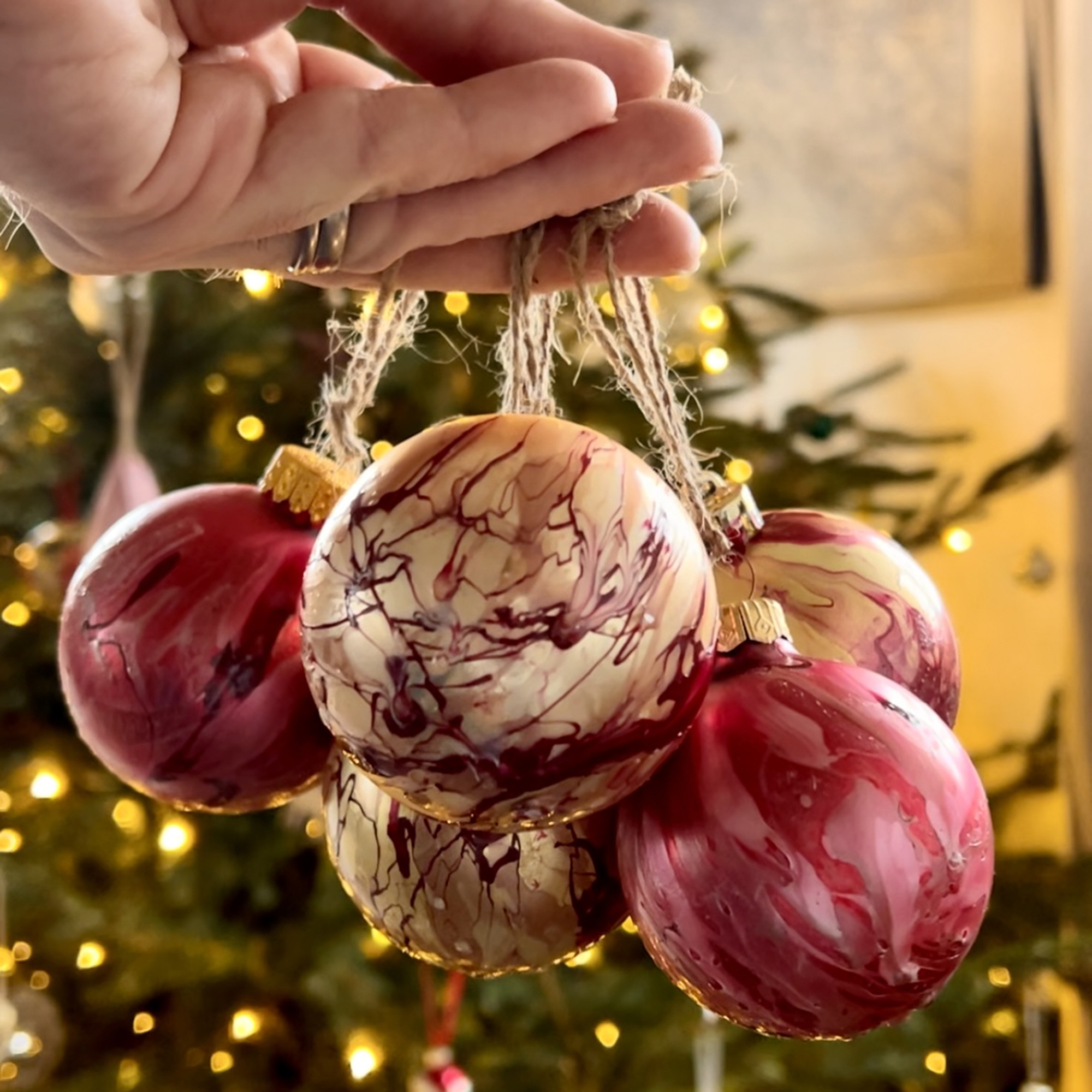 a cluster of home made marbled baubles held by hand