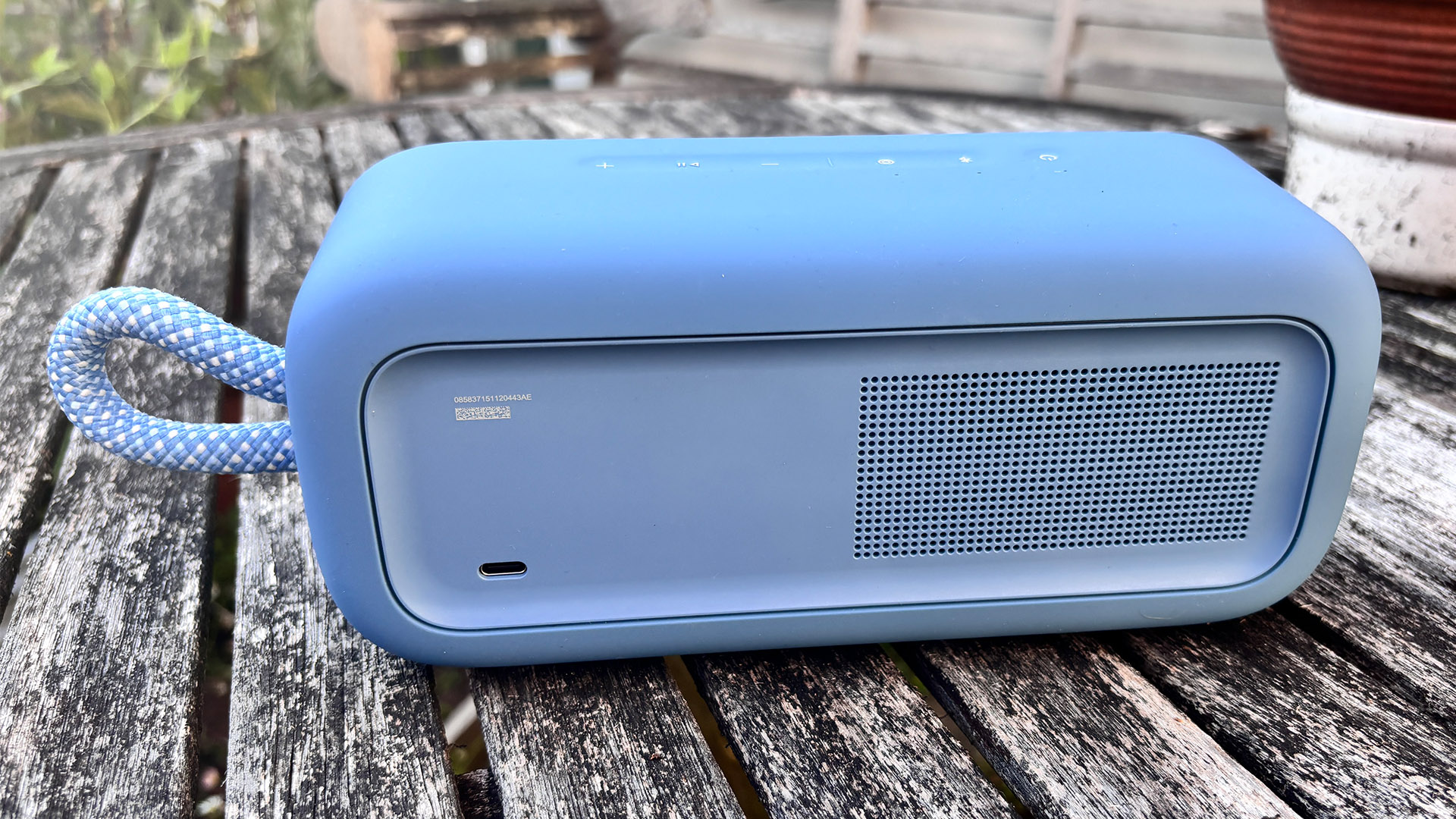 Bose SoundLink Plus wireless speaker on wooden garden table, rear of device showing grille and connection