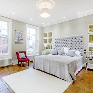 bedroom with grey headboard and wooden flooring