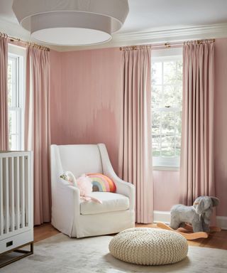Pink children's room with white armchair and rocking horse