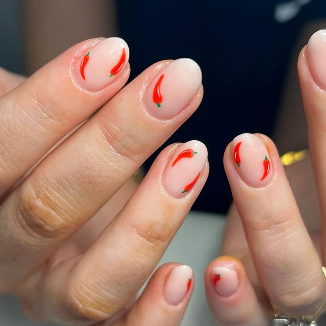 a nude manicure with red chili pepper designs