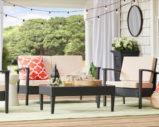 Front porch idea by Wayfair with dark grey outdoor furniture, red cushion and string lights