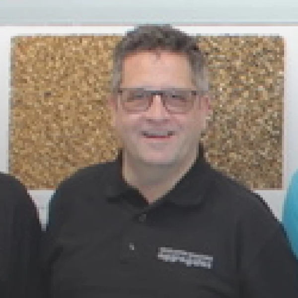 male with short grey hair, wearing glasses and black polo shirt
