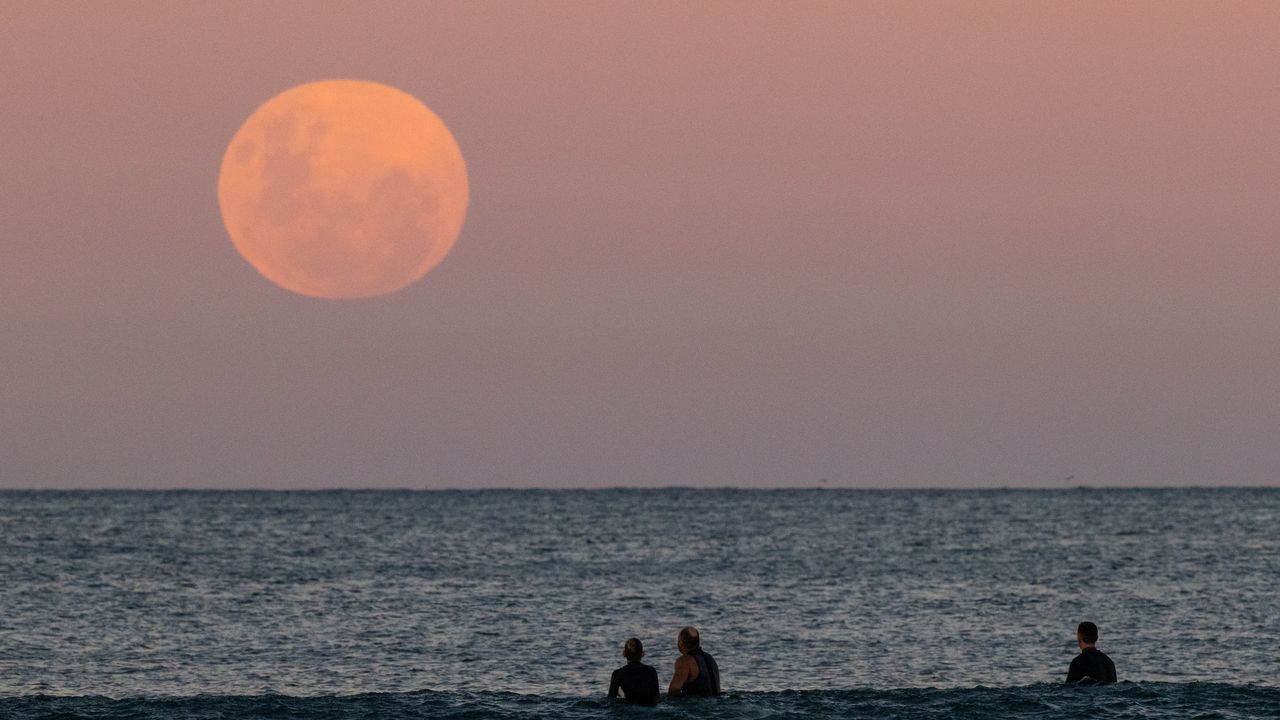 Beachgoers in Australia watch the full moon rise on May 26, 2021.
