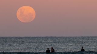 Beachgoers in Australia watch the full moon rise on May 26, 2021.