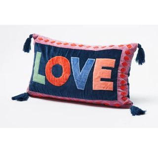 A velvet cushion with LOVE embroidered on it in multi-coloured threads