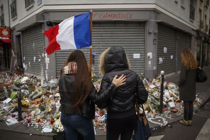 Two women stand outside the site of one of Friday's attacks in Paris.