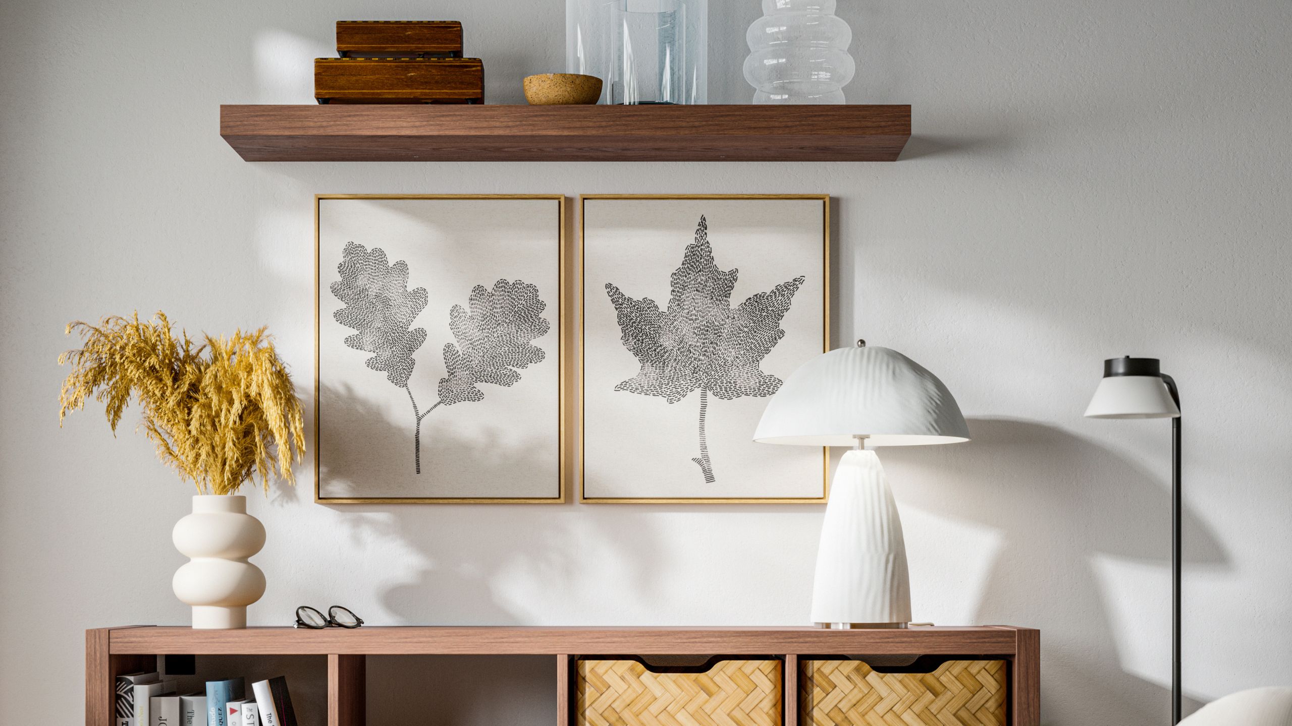 A close up of IKEA cabinets with a lamp, vase of flowers, floor lamp, two framed artworks of leaves, a floating timber shelf styled with vases and boxes
