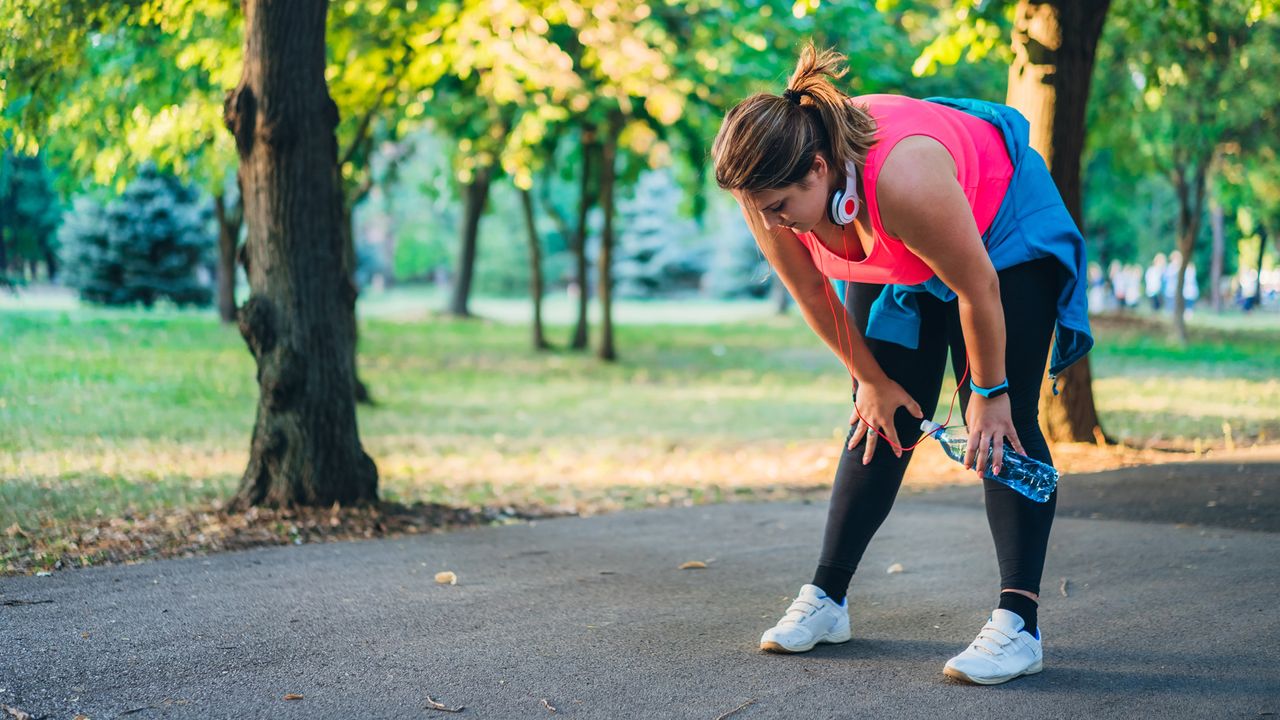 Young cute caucasian overweight woman exhausted after running in a public park.