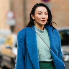 End of filler Jessica Wang wears a silver and gold pendant earrings, a pale green t-shirt, a dark green midi skirt, a blue fluffy oversized long coat,
