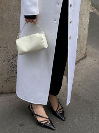 a close up photo of woman's work outfit with black slingback kitten heels with black trousers and a white coat