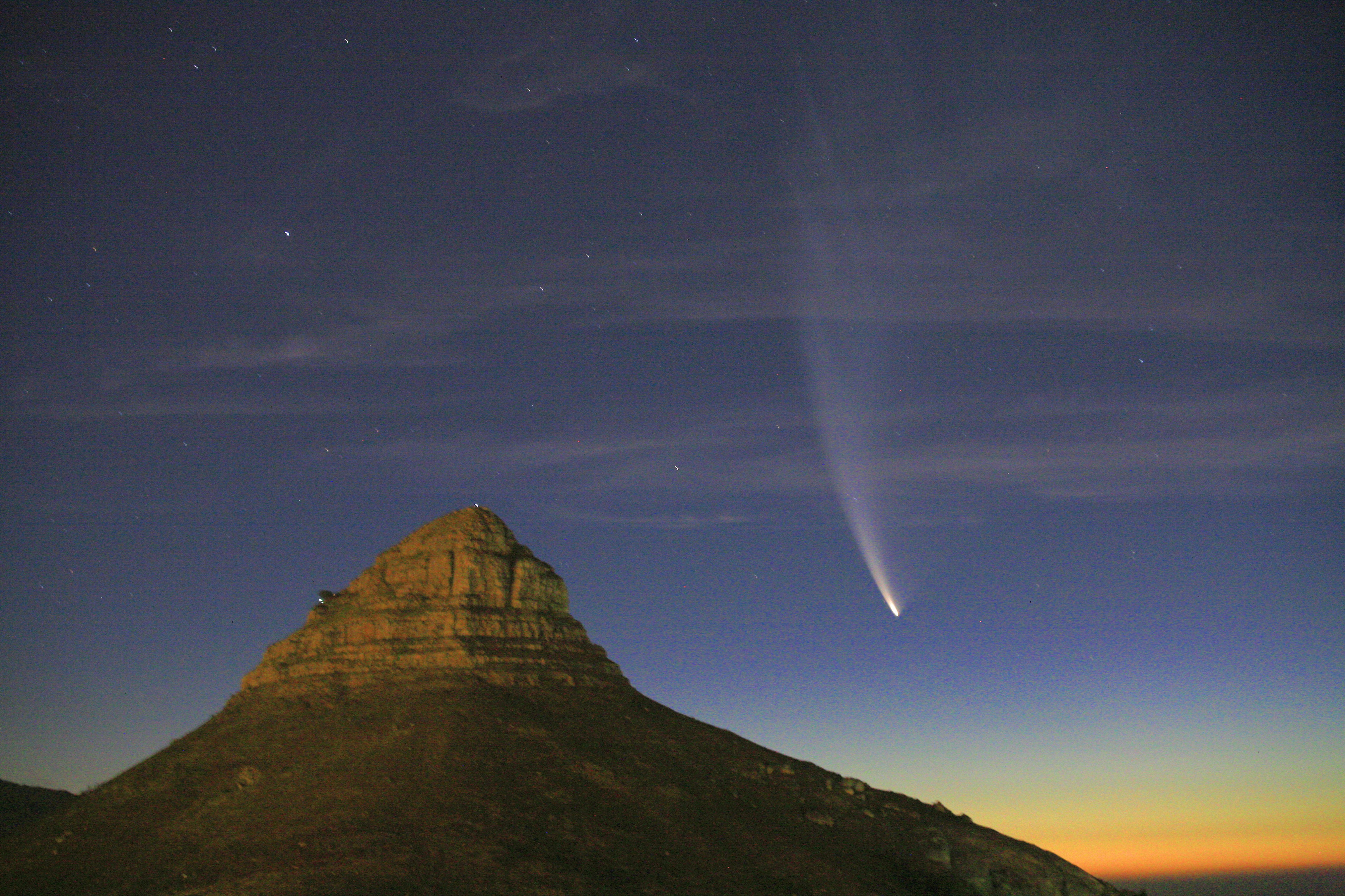 Ein heller Komet über einem Berg bei Sonnenuntergang