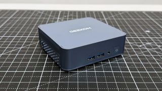 Geekom AX8 Pro AI Mini PC on a black mat against a white background.
