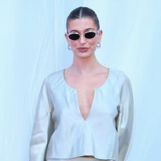 Hailey Bieber wearing sunglasses and a sleek bun. 