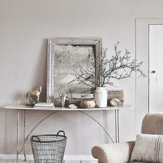 A rustic living room with grey walls and a decorative console table