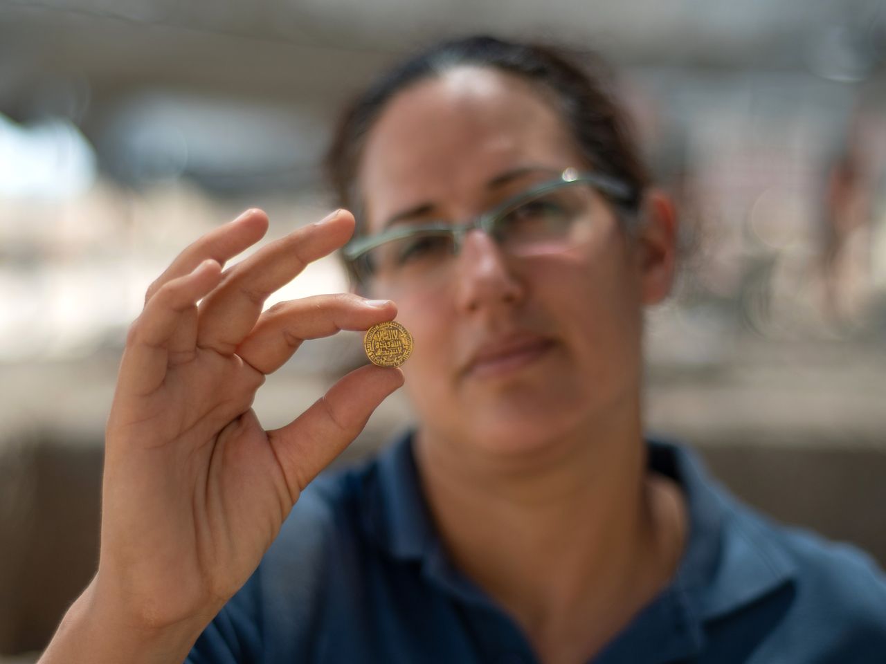 Liat Nadav-Ziv, director of the excavation, holds a gold coin.
