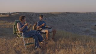 Frances McDormand and David Strathairn eating together in the great outdoors in Nomadland.