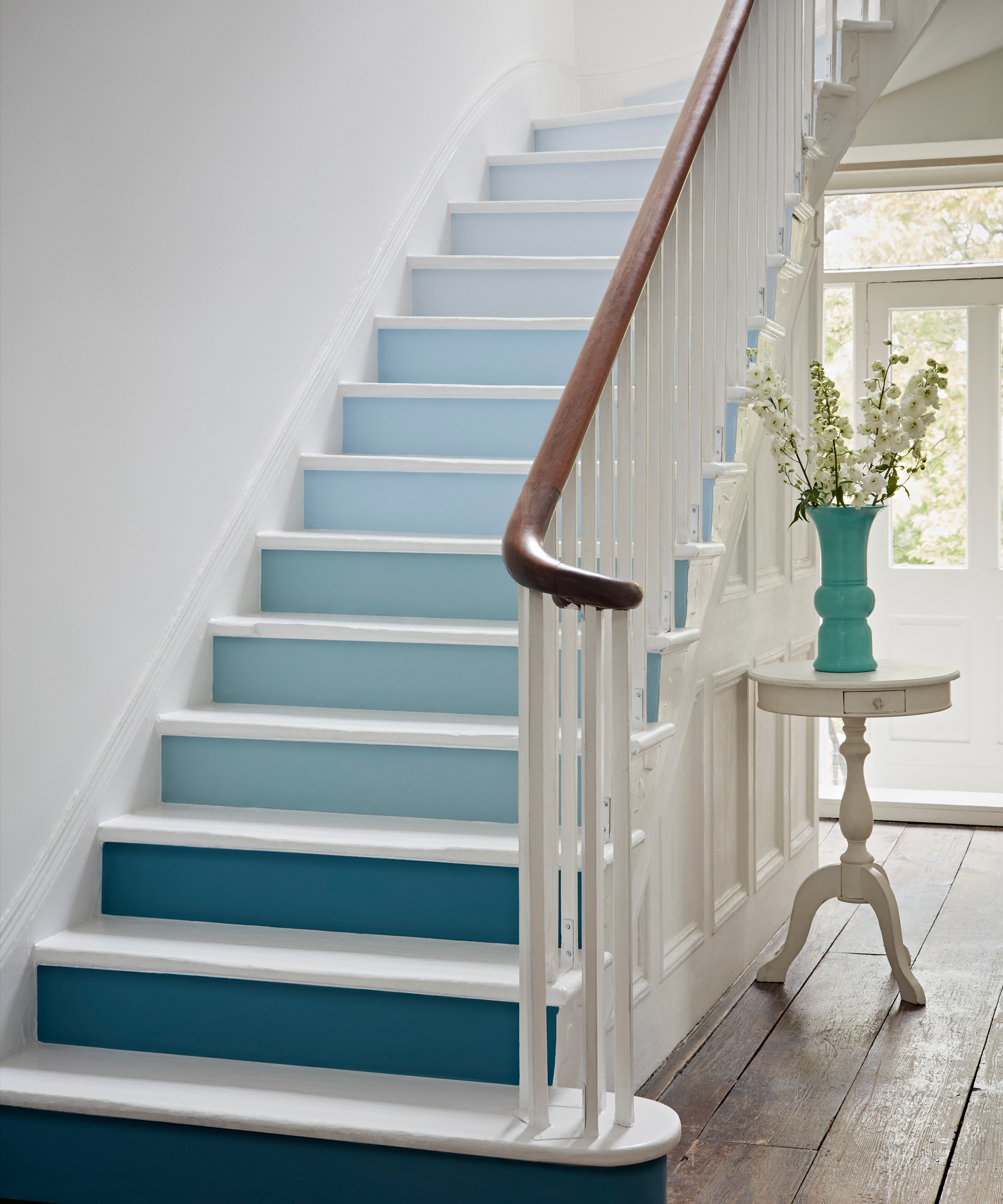 Stairs with blue ombre effect on risers in a traditional hallway