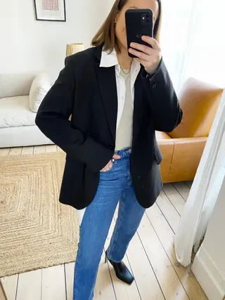 Woman wears black blazer, blue jeans and boots