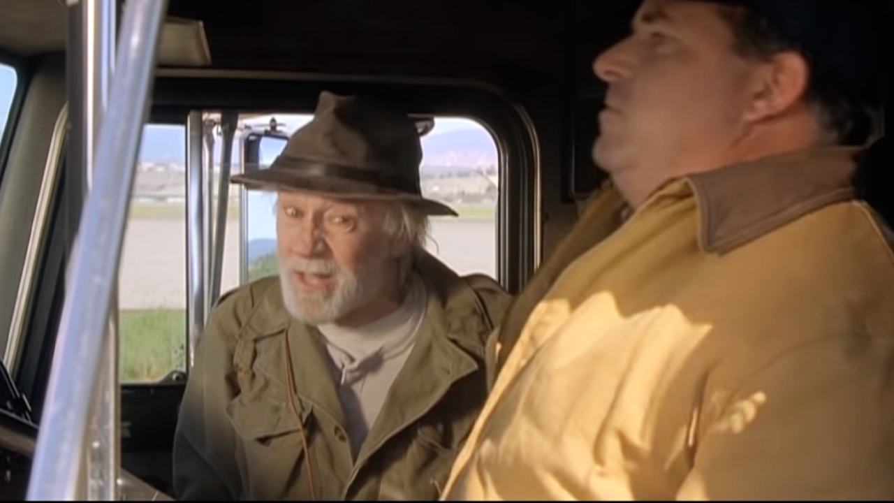 George Carlin wearing a hat and jacket catches a ride with a truck driver in Kevin Smith's 2001 comedy hit 