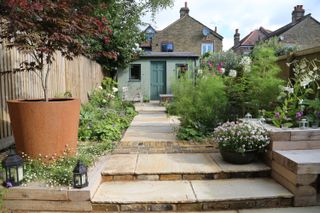 steps and paving leading through flowerbeds in a cottage style garden