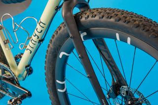 The front wheel and fork of the Stayer Groadinger gravel bike is pictured with a blue background.