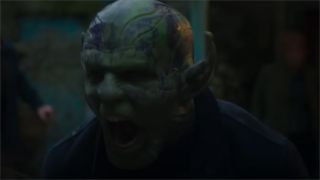 A still from Secret Invasion, a TV show from Marvel Studios. Here we see a close up of a screaming Skrull, an humanoid-looking alien with pointy ears and pale green skin covered in dark inky blue markings.