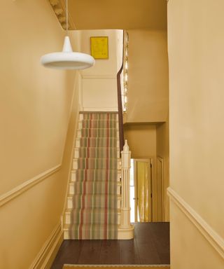 hallway color-drenched yellow with striped staircase runner