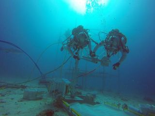 Two astronauts test out a drill that could be used in a future asteroid mission during NEEMO 18 in July 2014.