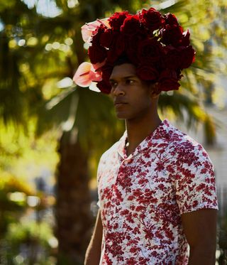 Man in patterned red flower shirt wearing a red flowers headdress
