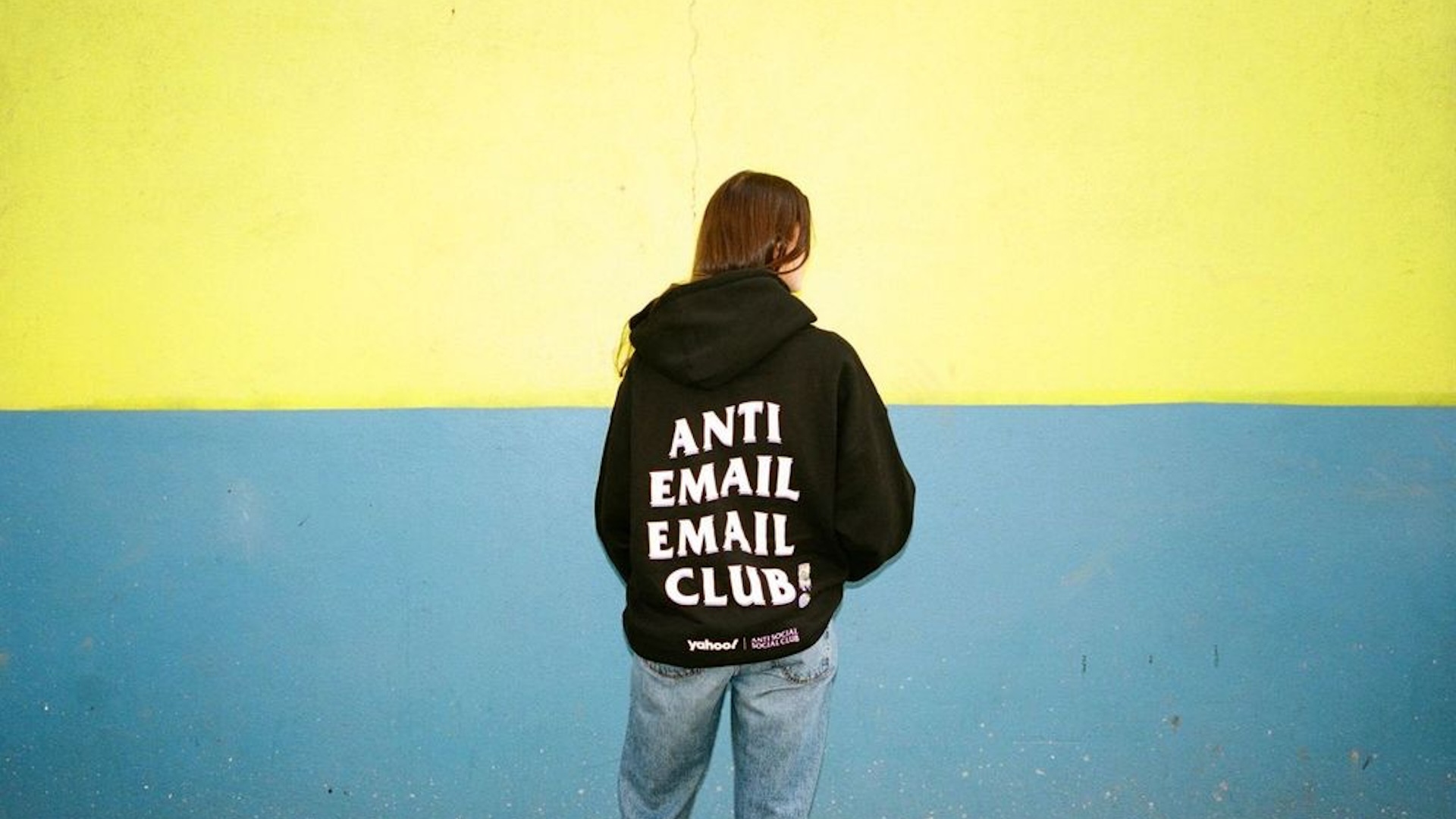 Anti Social Social Club black hoodie against a blue and yellow wall 
