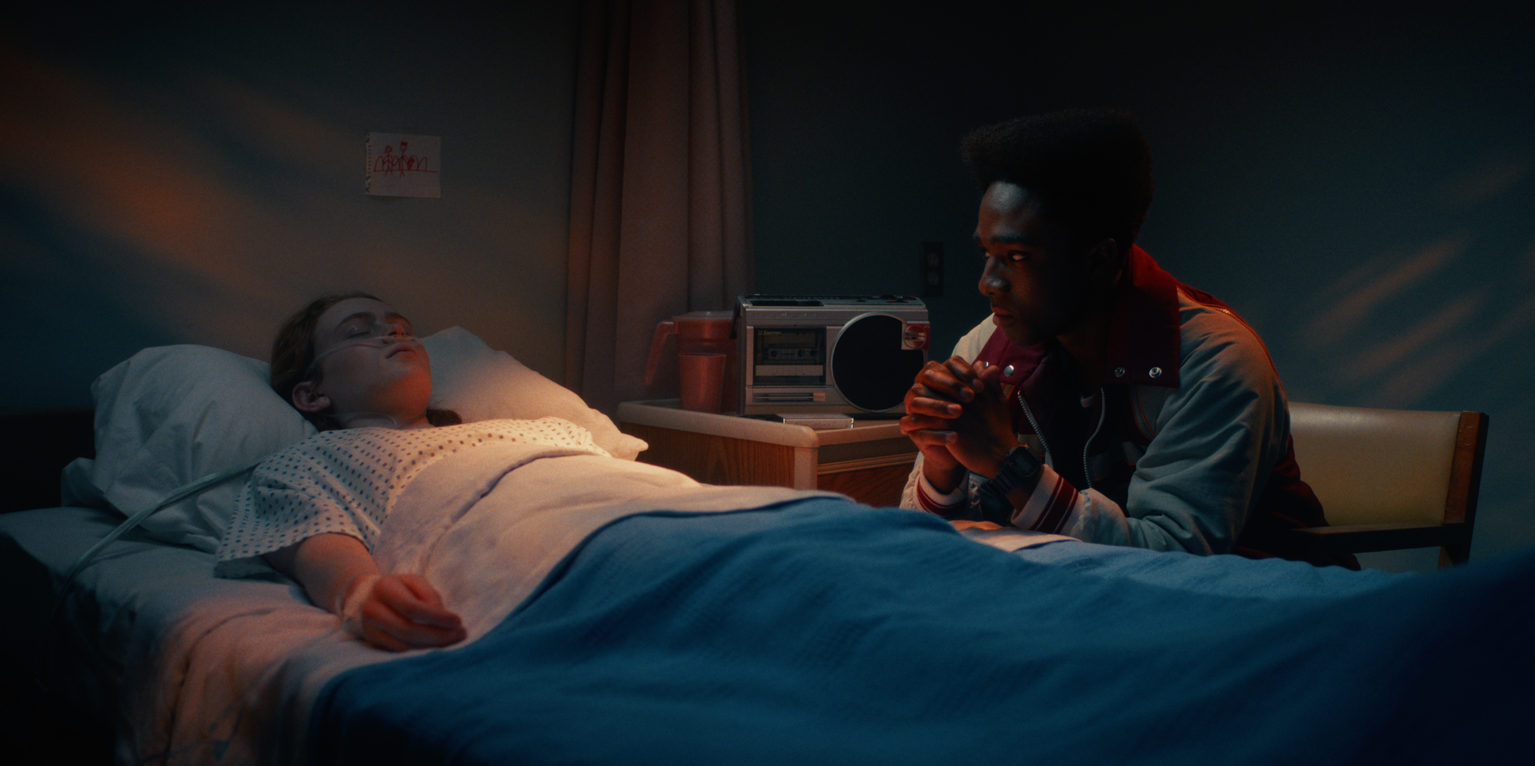 sadie sink as max and caleb mclaughlin as lucas as he sits at her bedside in the hospital in stranger things seaosn 5